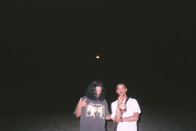 Rear view of couple standing against the sky at night