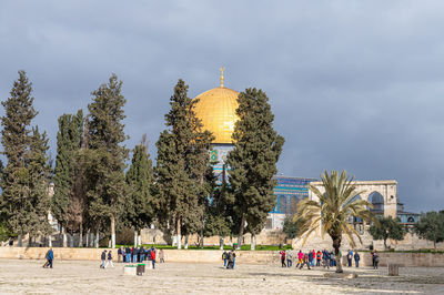 Group of people in temple against cloudy sky