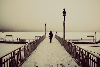 People walking on pier against clear sky