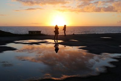 Silhouette of two women standing on beach