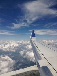 Airplane wing over cloudscape against sky