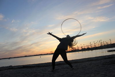 Silhouette person on beach against sky during sunset