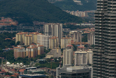 Buildings in city against tree mountain