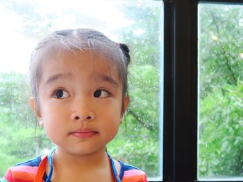 Portrait of cute girl seen through window