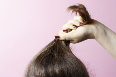 Close-up of woman with pink hair against white background