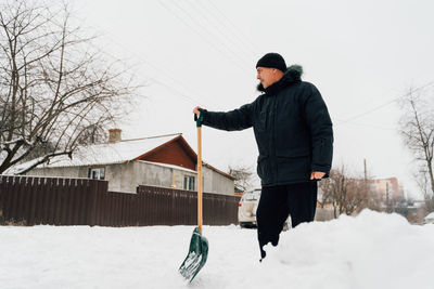 Snow collapse. senior man cleaning snow at winter weather with a shovel 