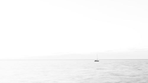 Sailboat in sea against clear sky