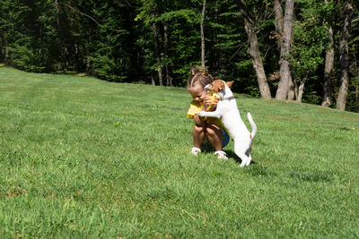 Rear view of woman playing with dog on field