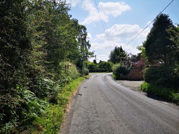 Road amidst trees against sky