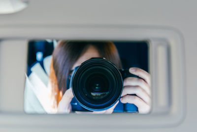 Close-up of man photographing with camera reflecting on mirror