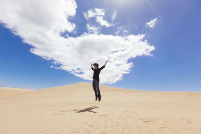 Full length of woman walking in desert against sky