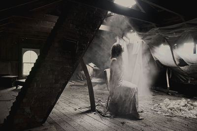 Rear view of woman sitting in corridor