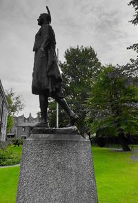 Statue in cemetery against sky