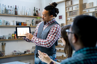 Businessman showing graphs on tablet computer to coworkers in office