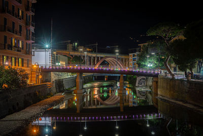 Illuminated bridge over river in city against sky at night