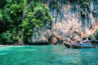 People in boat on sea against rock