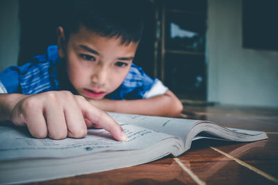 Portrait of boy with book on table