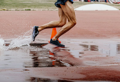 Male runner athlete running steeplechase in athletics