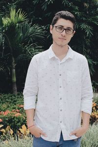 Portrait of young man standing against plants