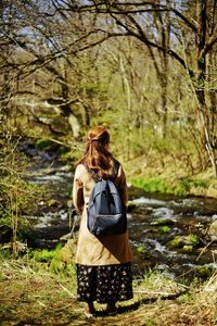 Rear view of woman standing against trees