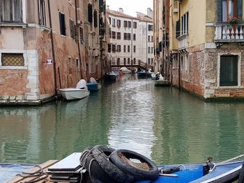 Boats moored on canal amidst buildings in city