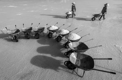 High angle view of men collecting salt with wheelbarrows