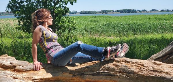 Woman sitting on rock against plants