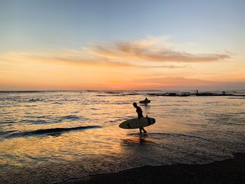 Silhouette man on beach against sky during sunset