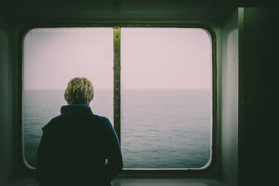 Rear view of man looking through window