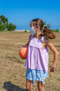 Rear view of girl on field against sky