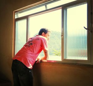 Rear view of woman looking through window