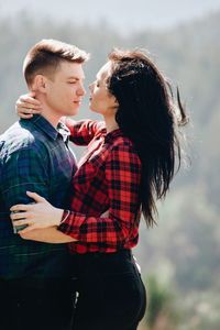 Side view of young couple standing face to face in forest