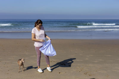 Woman with dog at beach against sky