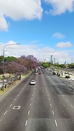 Vehicles on road against cloudy sky