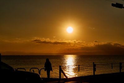 Silhouette people on sea against sky during sunset