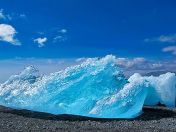 Glacial ice on sea shore against sky