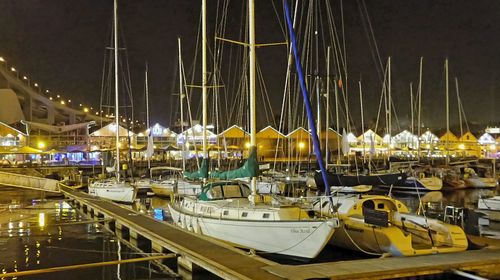 Sailboats moored in harbor at night