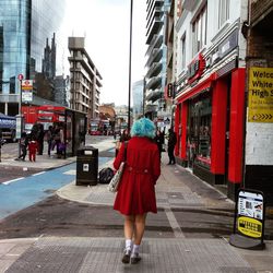 Rear view of woman walking on street amidst buildings