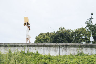 Woman with arms raised against sky