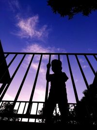 Low angle view of silhouette boy playing against blue sky
