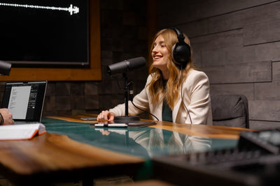 Closeup of young woman in headphones using microphone while working