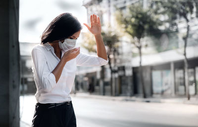 Midsection of woman holding umbrella standing in city