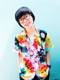 Portrait of smiling young woman standing against wall