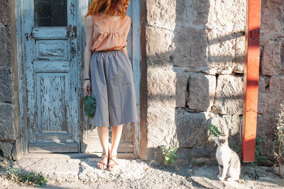 Young woman standing by cat at doorway