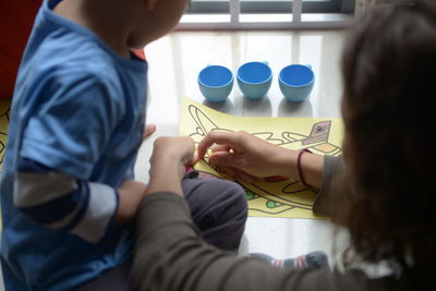 High angle view of mother and son coloring on table at home