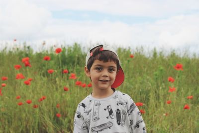 Portrait of boy standing on field against sky