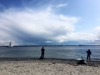 Men standing on beach against sky