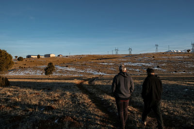 Rear view of man standing on field against clear sky