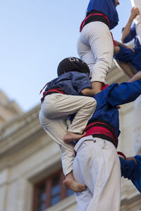 Low angle view of people climbing against clear sky