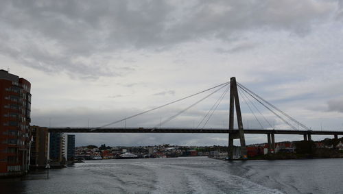 Bridge over calm sea against cloudy sky
